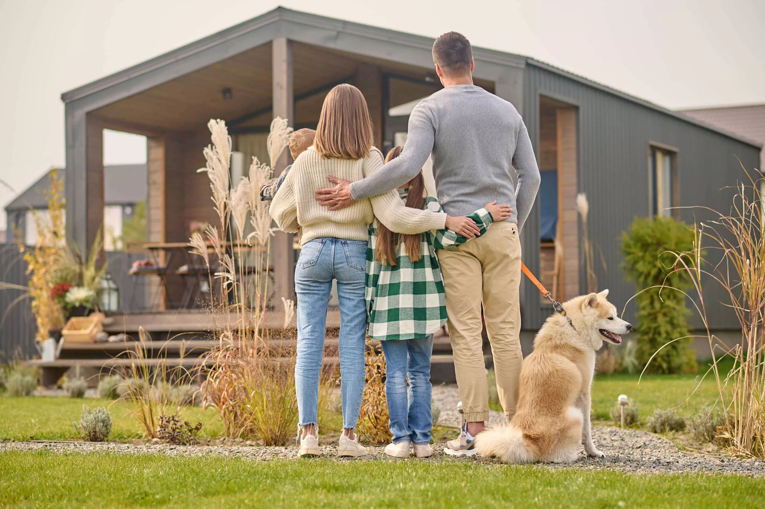 Happy family standing outside and looking at their home with satisfaction